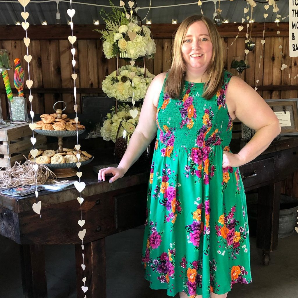 Kate Johnson in a green floral dress standing in front of a banquest table; clear path