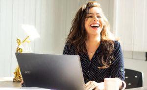 Woman Smiling in front of the computer; system for virtual assistants