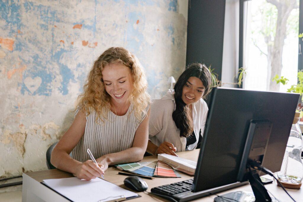 Women writing in front of computer